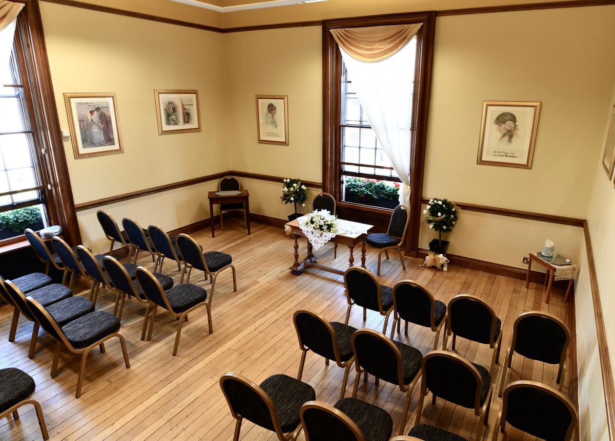 Room at town hall with rows of seats for a wedding ceremony and a table for the couple at the front